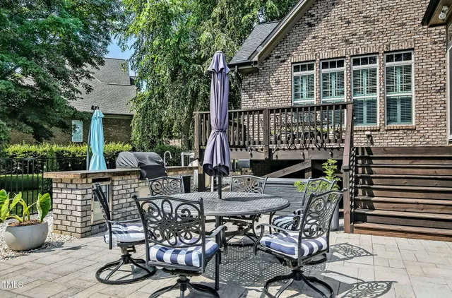 a view of a patio with table and chairs potted plants and floor to ceiling window