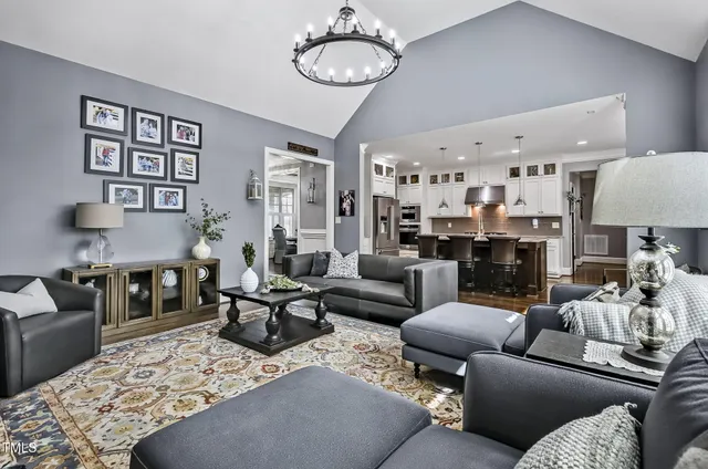 a living room with furniture kitchen view and a chandelier