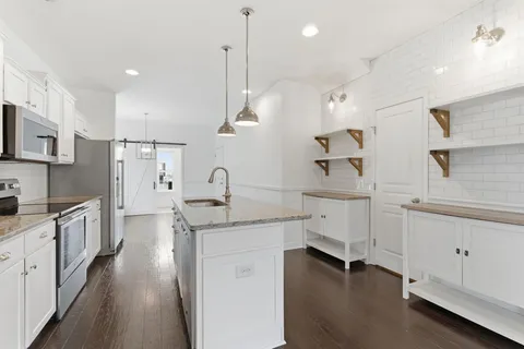a kitchen with white cabinets appliances and a window