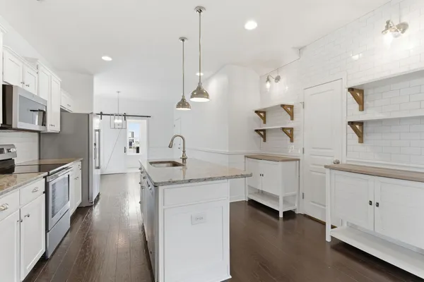a kitchen with white cabinets appliances and a window
