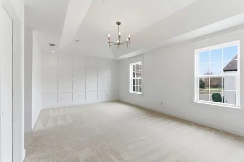 an empty room with windows and chandelier fan