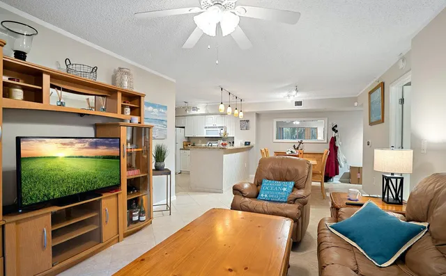 a living room with furniture a flat screen tv and kitchen view
