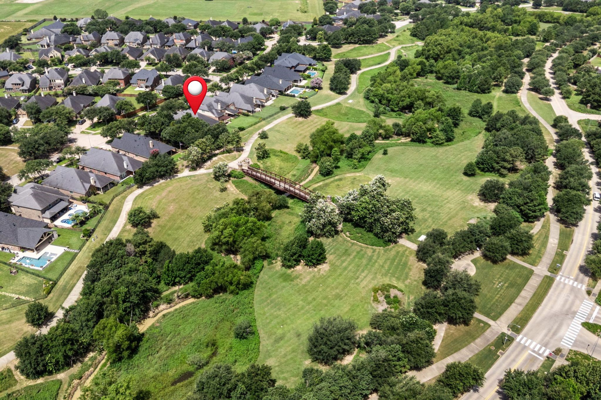 27642 Linden Ridge Lane Fulshear, TX 77441 - Photo 38 of 42 One last aerial view showcases the home and surrounding area, highlighting the property’s placement within the neighborhood and the expansive natural surroundings.