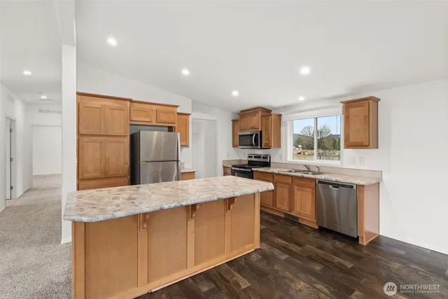 a kitchen with granite countertop a sink stainless steel appliances and a window