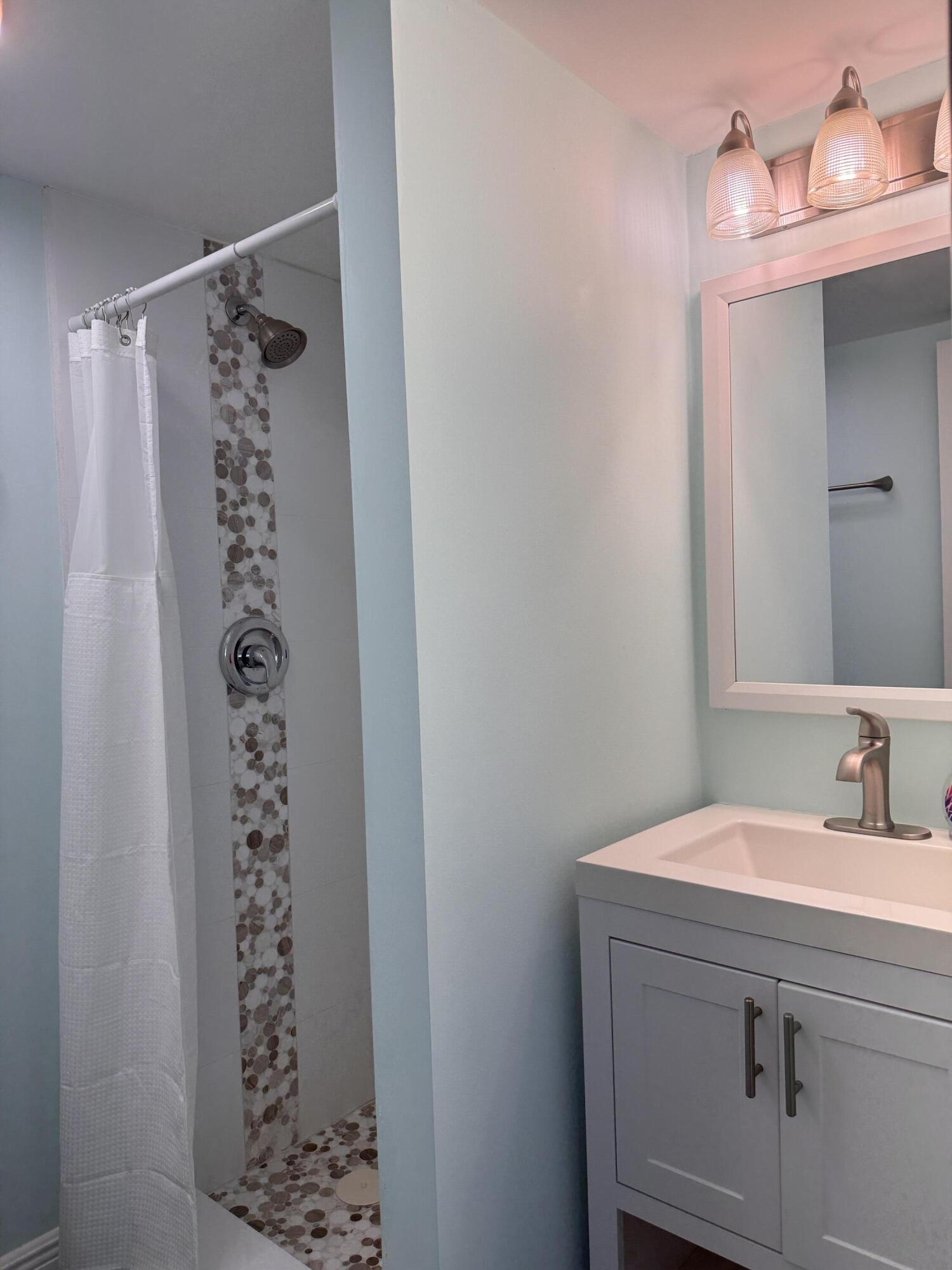 88540 Overseas Highway, Unit 203 Tavernier, FL 33070 - Photo 12 of 35 a bathroom with a sink a mirror and a shower