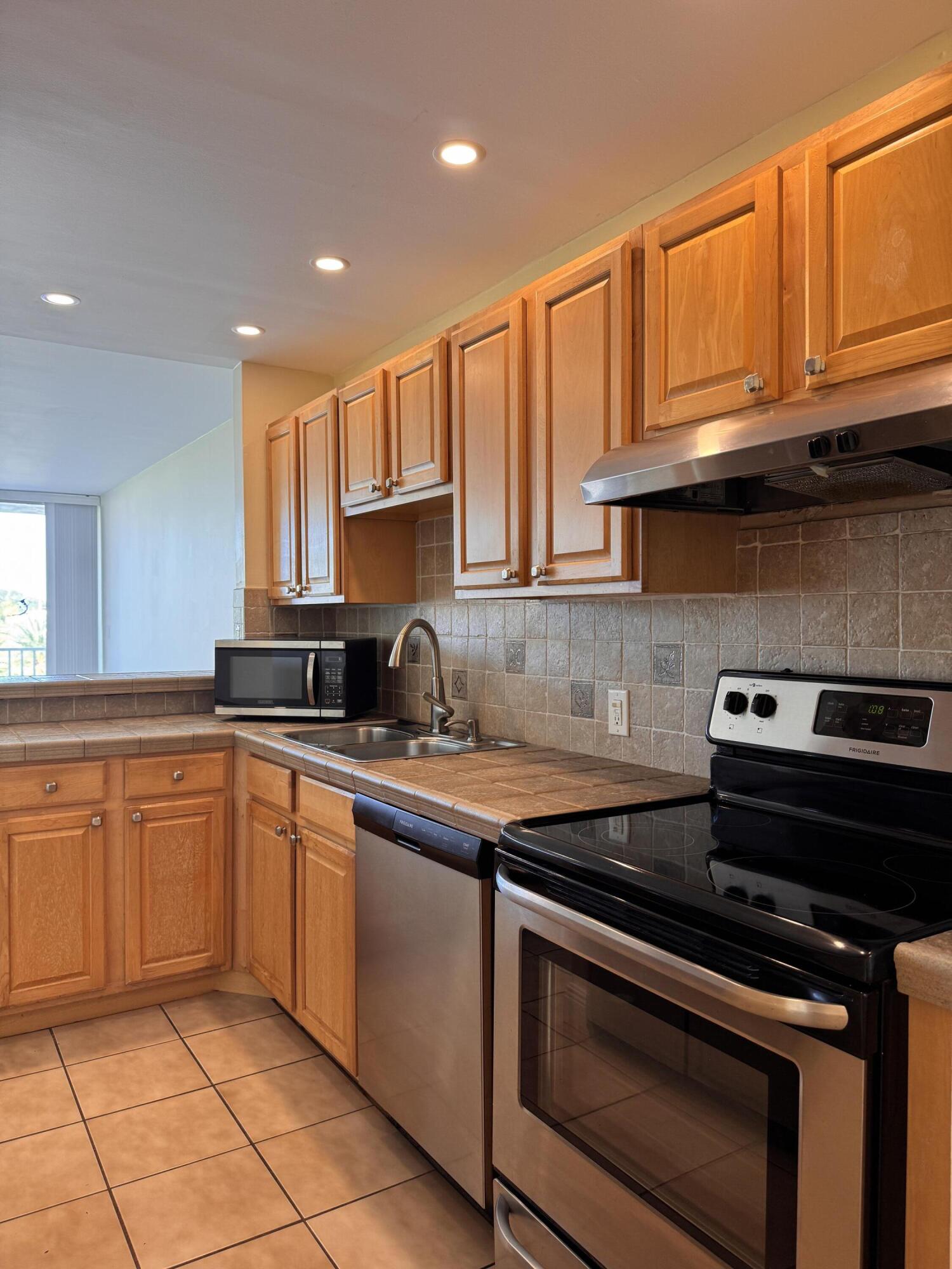 88540 Overseas Highway, Unit 203 Tavernier, FL 33070 - Photo 17 of 35 a kitchen with stainless steel appliances granite countertop a stove a sink and a microwave