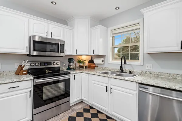 a kitchen with granite countertop white cabinets white stainless steel appliances and a sink