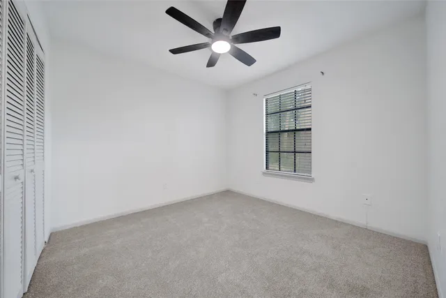an empty room with windows and ceiling fan