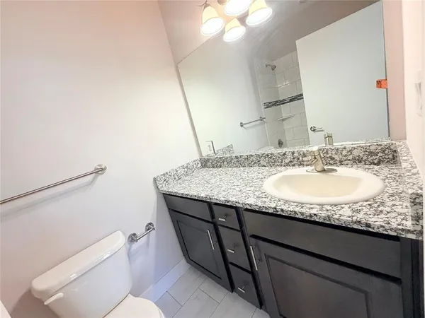 a bathroom with a granite countertop sink a toilet and a mirror
