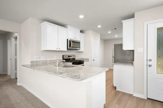 a kitchen with kitchen island granite countertop a sink a stove a refrigerator a microwave and cabinets