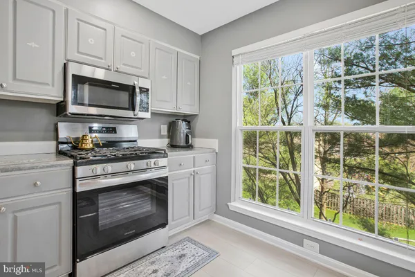 a kitchen with stainless steel appliances granite countertop white cabinets and a stove top oven