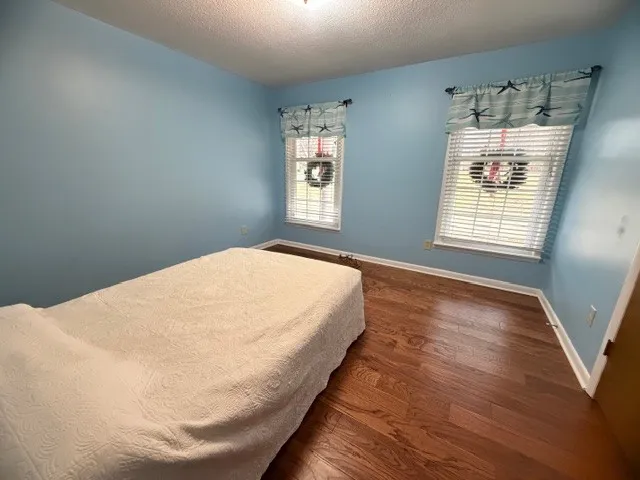 a view of a bedroom with wooden floor and windows