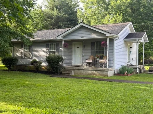 a front view of a house with a garden and trees