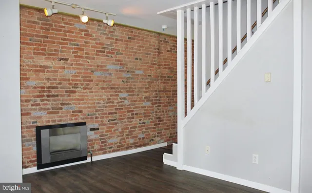 a view of an empty room with wooden floor and a fireplace