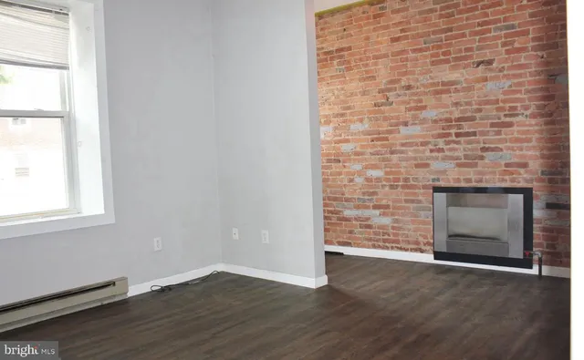 an empty room with wooden floor fireplace and window
