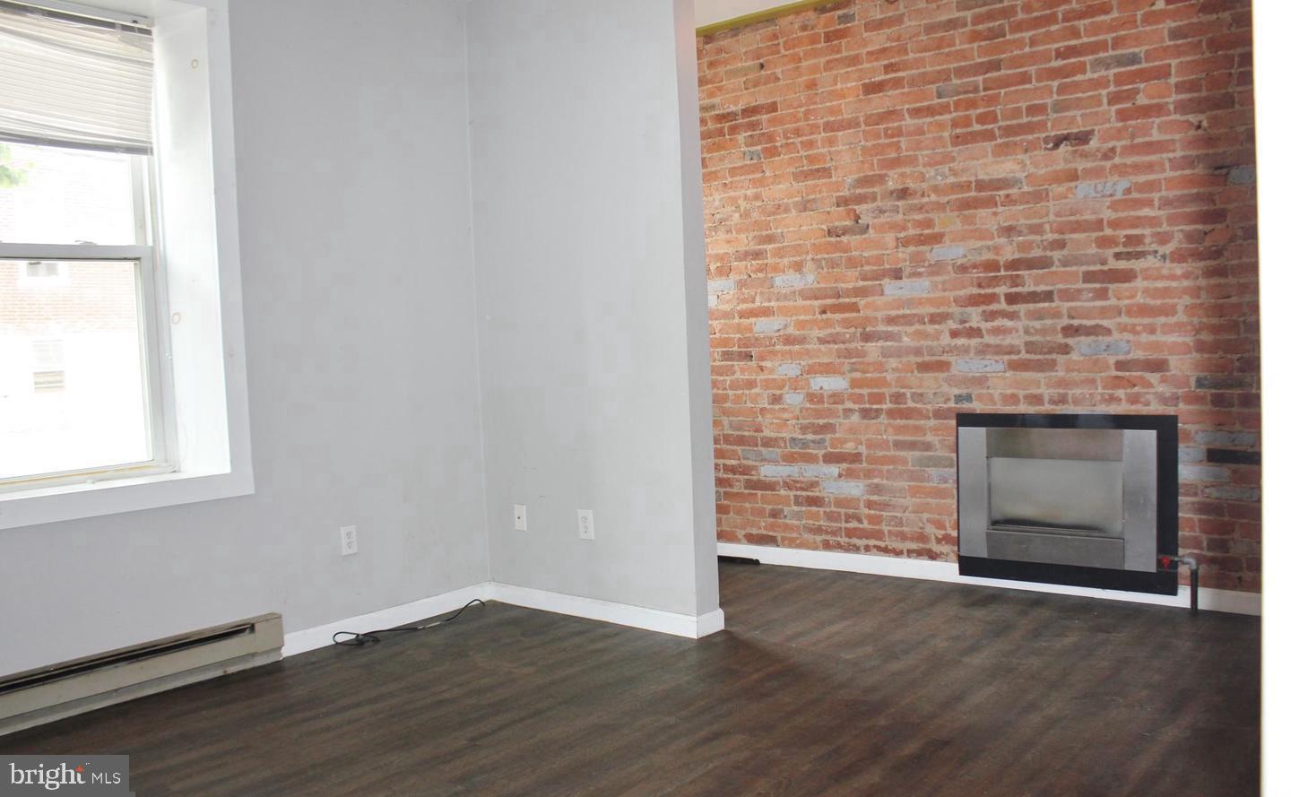 236 North Locust Street Hagerstown, MD 21740 - Photo 5 of 22 an empty room with wooden floor fireplace and window