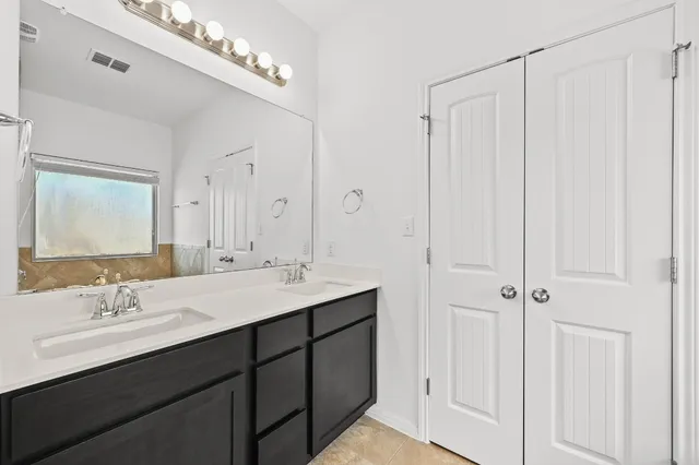 a bathroom with a double vanity sink a mirror and a shower