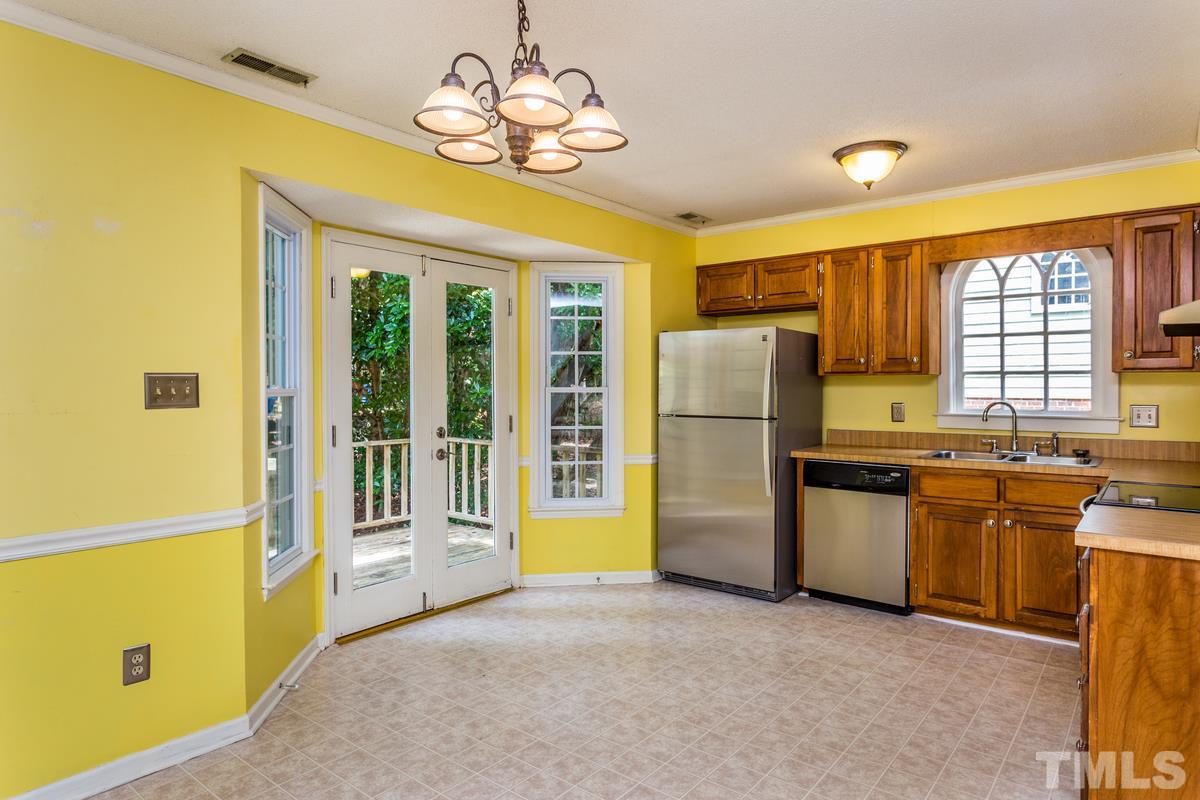 6908 Sandringham Drive Raleigh, NC 27613 - Photo 5 of 21 a kitchen with stainless steel appliances granite countertop a refrigerator a stove a sink dishwasher a dining table and chairs with wooden floor