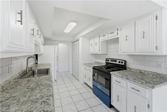 a kitchen with granite countertop a stove a sink and a refrigerator