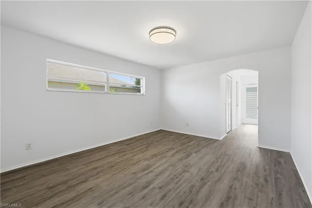 an empty room with wooden floor and window