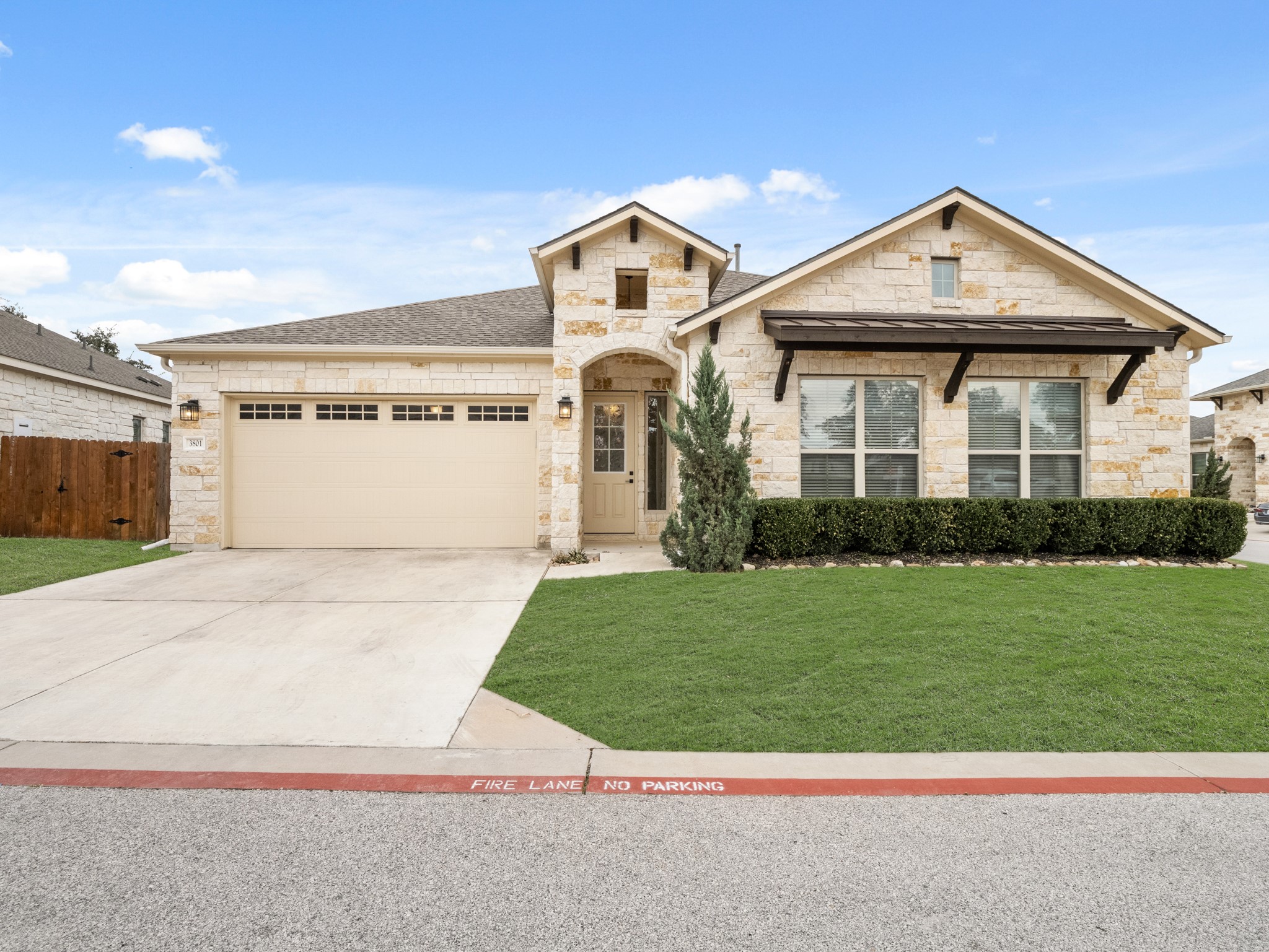 French country style house with stone siding, concrete driveway, an attached garage, and roof with shingles