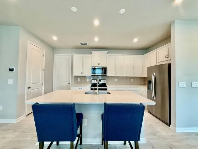 a kitchen with stainless steel appliances granite countertop a table chairs sink refrigerator and microwave