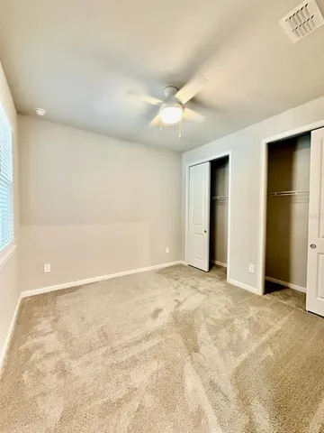a view of an empty room with closet and a window