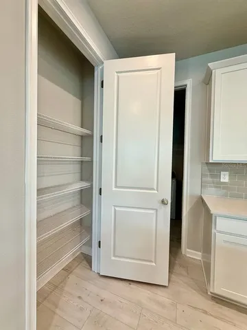 a view of a kitchen with white cabinets and a refrigerator