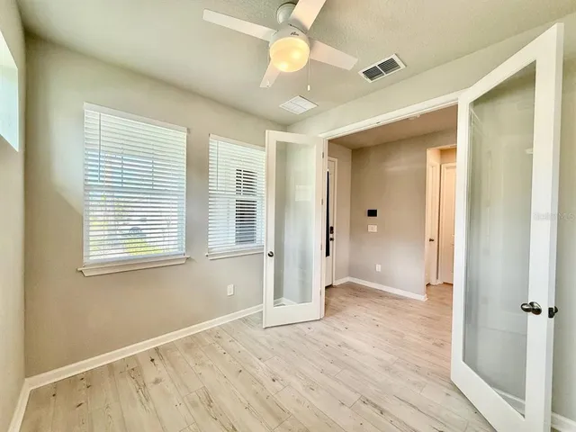 a view of an empty room with wooden floor and a window