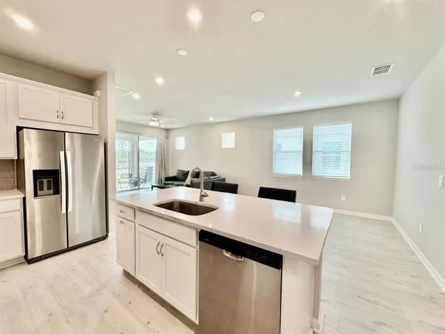 a kitchen with a sink a stove a refrigerator and white cabinets