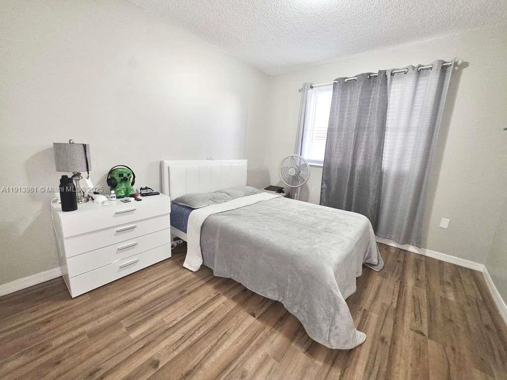 15871 Southwest 86th Terrace Miami, FL 33193 - Photo 20 of 30 a bedroom with a bed and wooden floor