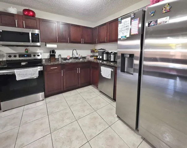a kitchen with granite countertop a refrigerator and a stove top oven
