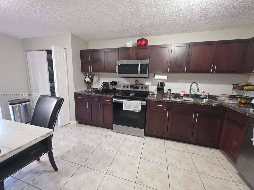 15871 Southwest 86th Terrace Miami, FL 33193 - Photo 7 of 30 a kitchen with stainless steel appliances granite countertop a stove a sink dishwasher and a refrigerator