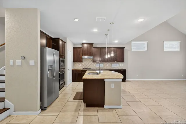 a kitchen with stainless steel appliances granite countertop a refrigerator and a stove