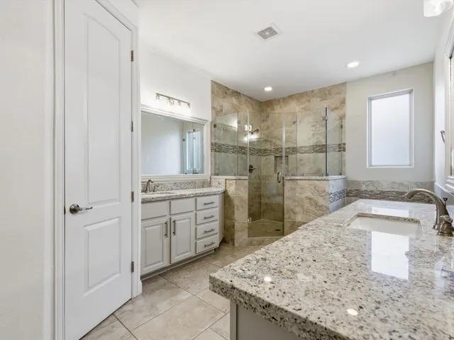 a bathroom with a granite countertop sink a mirror and a shower