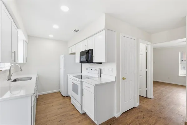 a hallway with white cabinets and stainless steel appliances