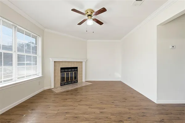 an empty room with chandelier fan and windows