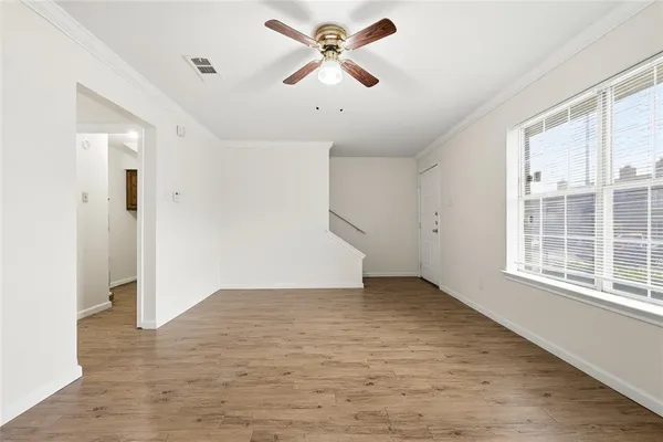 an empty room with chandelier fan and windows