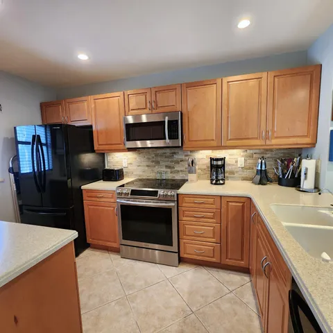 a kitchen with stainless steel appliances granite countertop a refrigerator stove microwave sink and cabinets