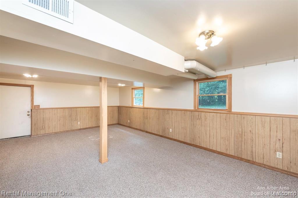 7870 Chamberlin Road Dexter, MI 48130 - Photo 36 of 52 Carpeted room featuring wood paneling, multiple windows, and a ceiling-mounted light fixture