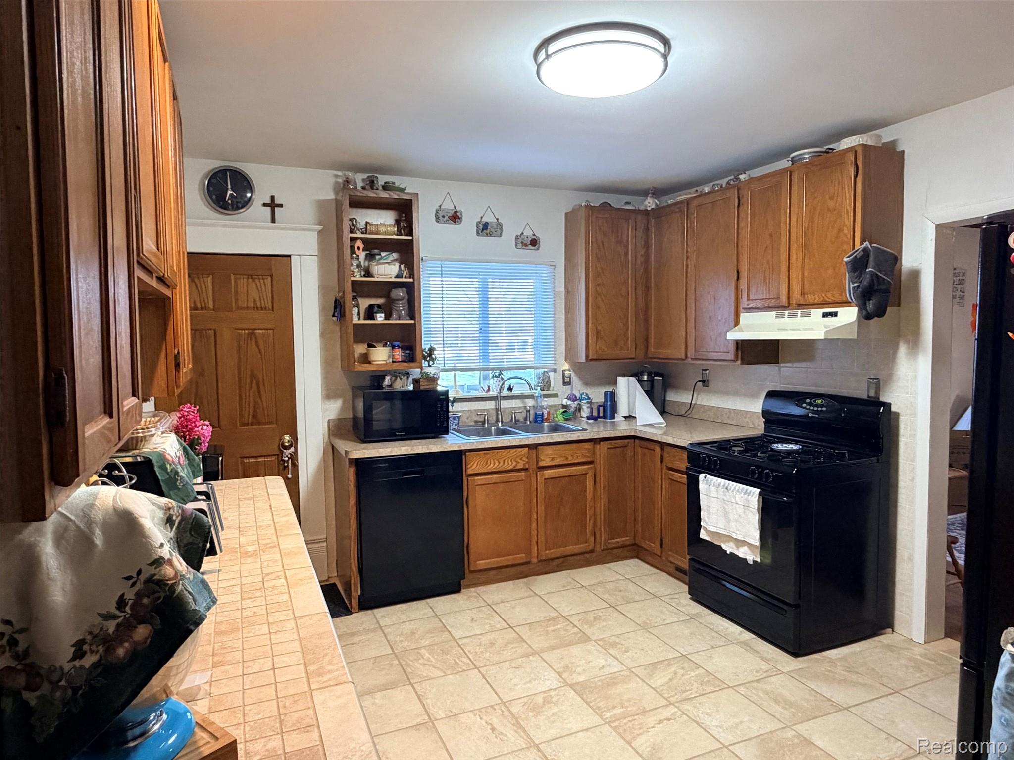 6038 Byron Road Howell, MI 48855 - Photo 10 of 24 Kitchen with black appliances, light countertops, wood finish cabinets, and open shelves