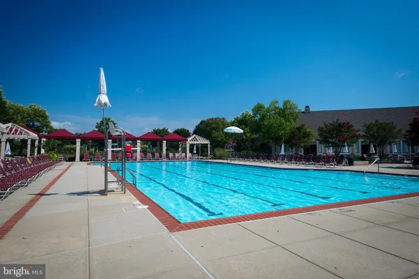 a view of swimming pool with red chairs in front of main door