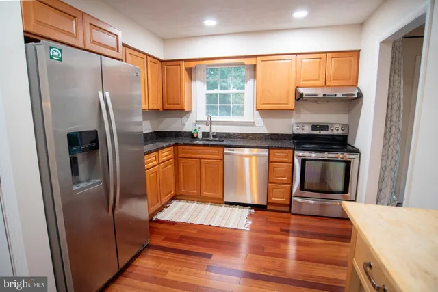 a kitchen with granite countertop stainless steel appliances a sink and a refrigerator
