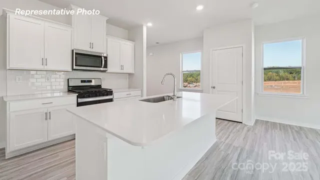 a kitchen with stainless steel appliances a microwave a stove a sink dishwasher and a refrigerator with wooden floor