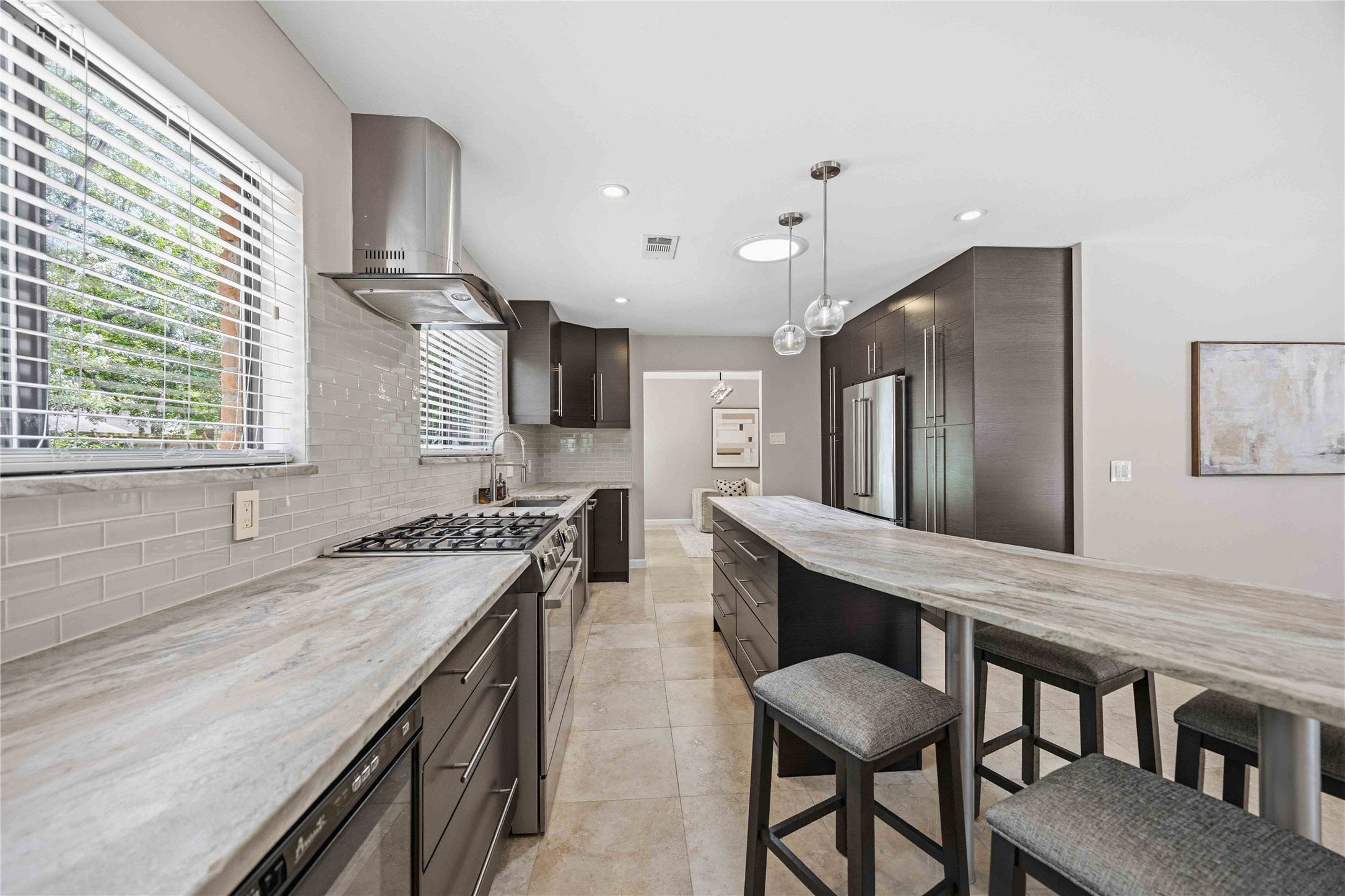 619 Rancho Bauer Drive Houston, TX 77079 - Photo 20 of 46 Gourmet kitchen featuring custom cabinetry, leathered granite countertops, soft-close drawers and cabinets, pull-out shelving, abundant storage, a spacious breakfast bar, and direct access to a versatile living space ideal for formal dining or an additional family room