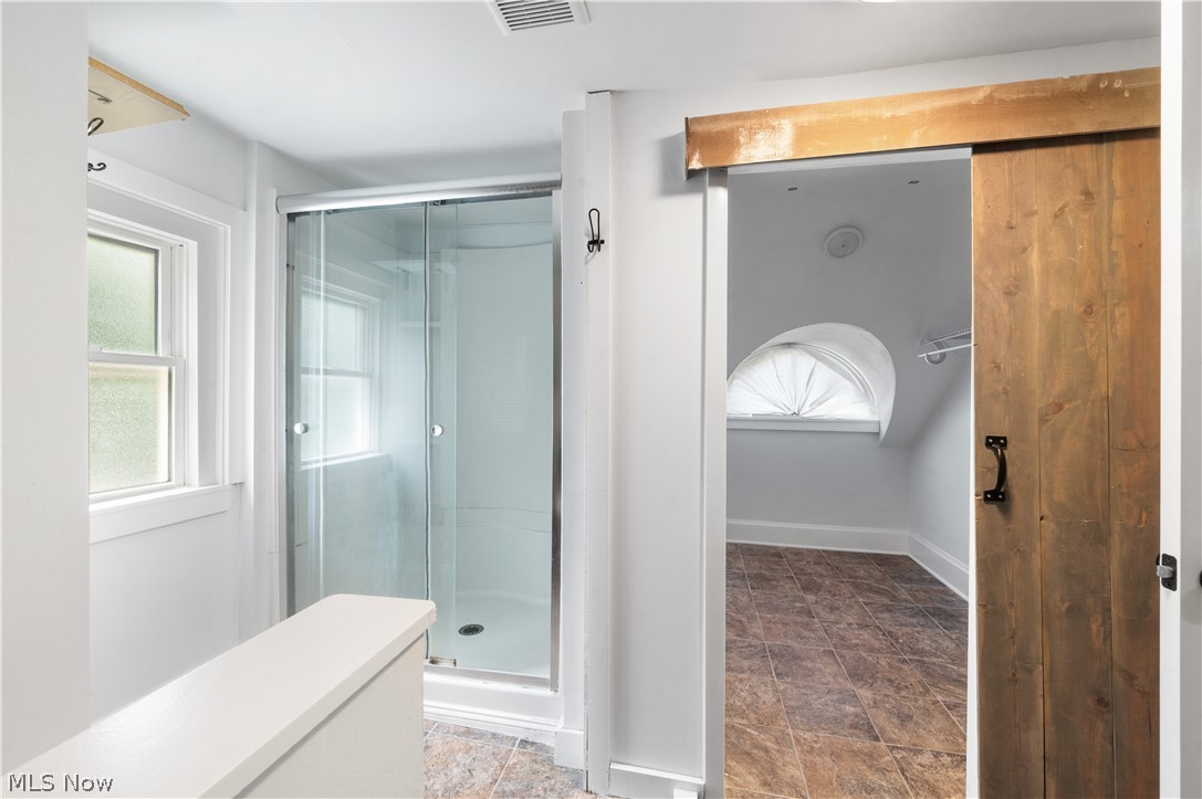 371 Merriman Road Akron, OH 44303 - Photo 23 of 27 Glass-enclosed shower with white surround, frosted window, and wood-finish barn door entry to an additional space featuring an arched window