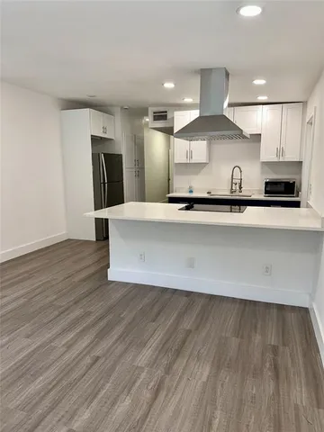 a large kitchen with stainless steel appliances a large counter top a stove and a wooden floors