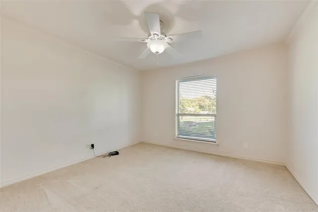 an empty room with a window and a fan