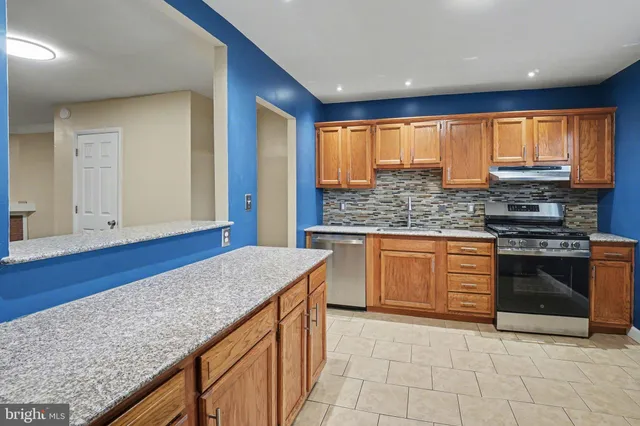 a kitchen with stainless steel appliances granite countertop a stove a sink and a microwave