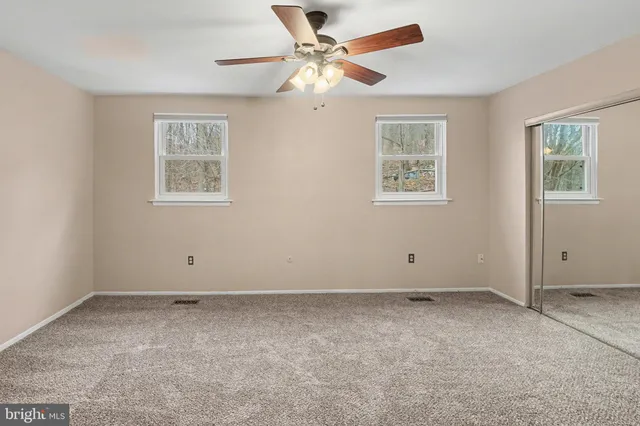 an empty room with closet and a chandelier fan